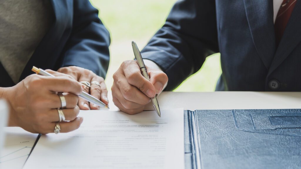Signing a business contract. A group of business people at the m Signing a business contract. A group of business people at the meeting and sign a together business investment agreement.