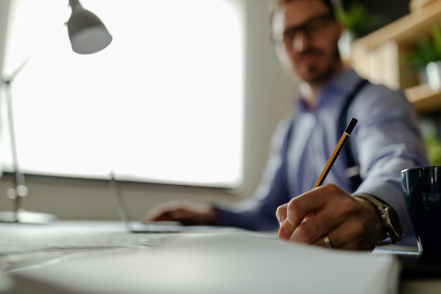 Interior designer is reviewing blueprints and holding pencil dra Interior designer or architect reviewing blueprints and holding pencil drawing on desk at home office.